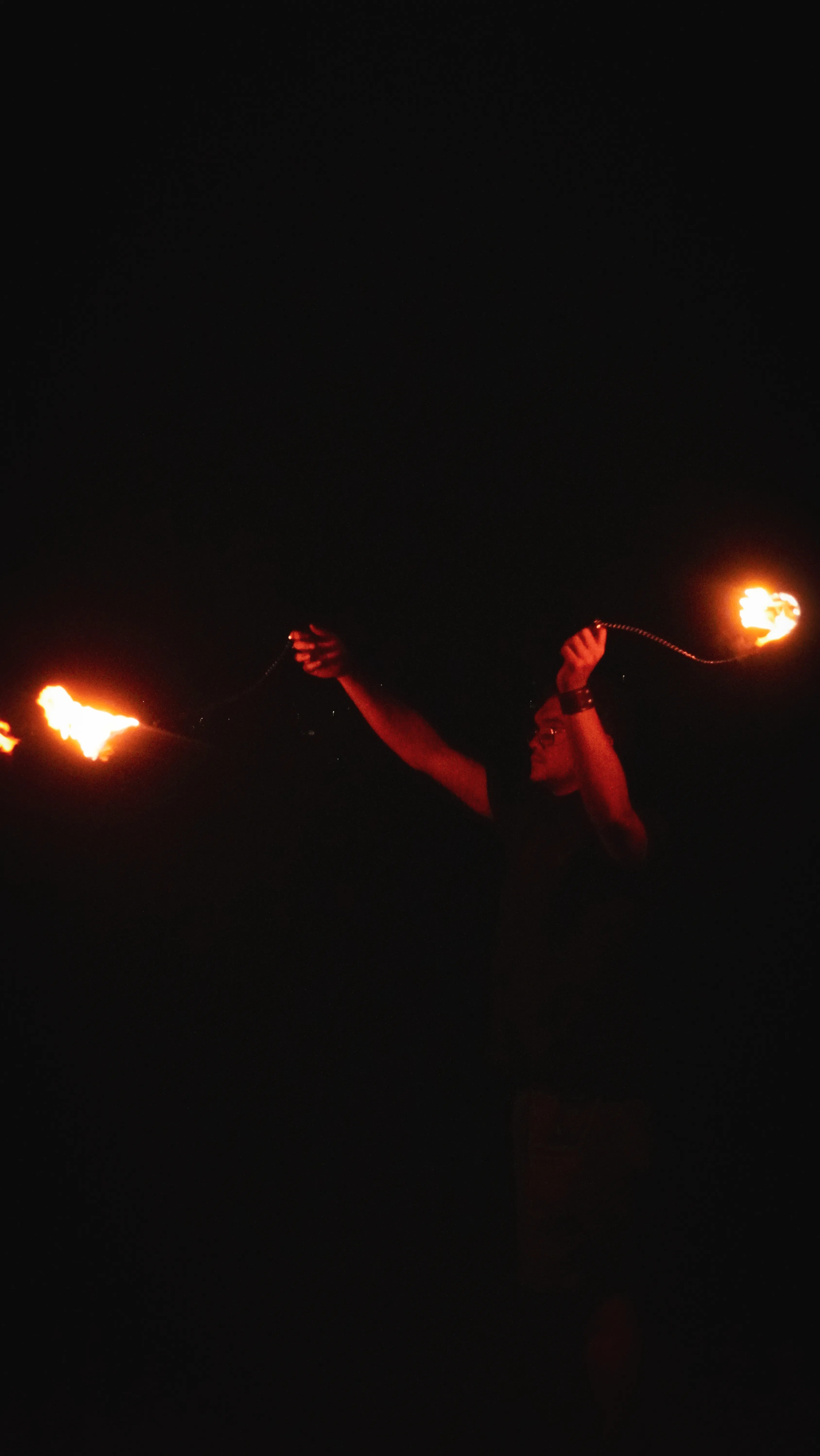 Artiste performer feu lors d'un évènement en plein show, fait tourner au dessus de sa tête des bolas enflammées.