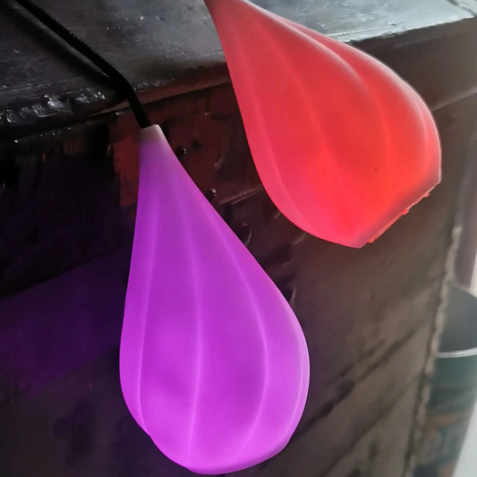 Bolas LED lumineuses RGB, Aurora Poi, en fonctionnement avec les modes rouge et violet posées sur un coffre ancien.