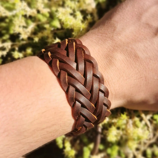 Bracelet en cuir pour homme ou femme sur fond végétal.