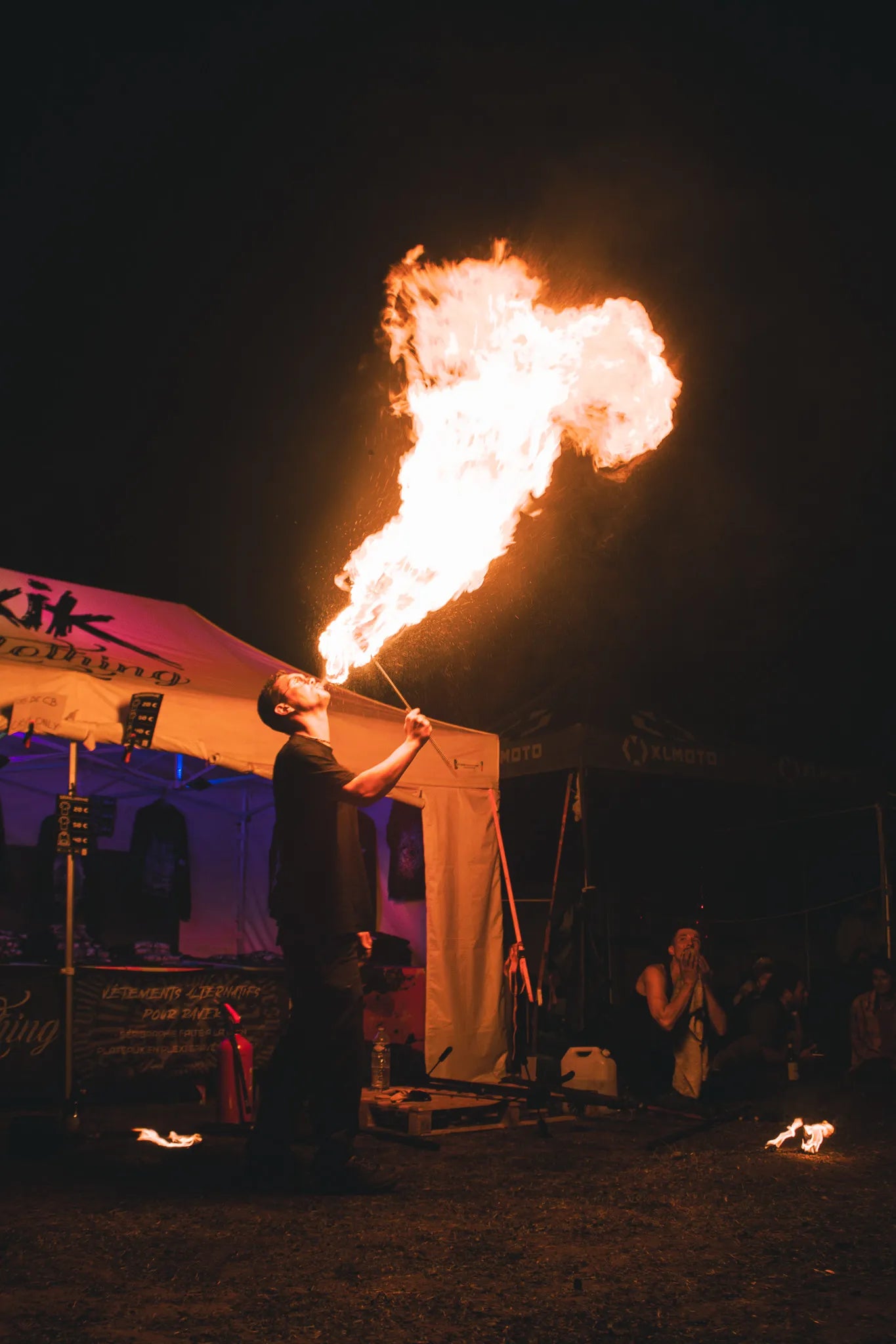 Cracheur de feu lors d'un spectacle feu, crachant une boule de feu dans la nuit devant un public.